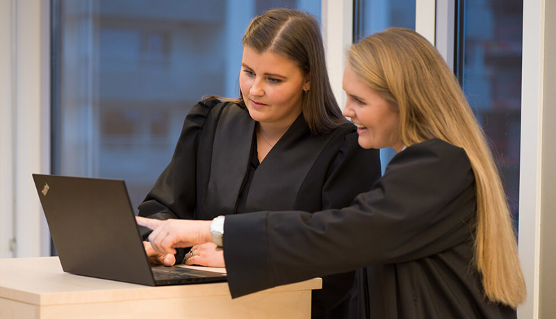 To advokater i advokatkapper ser på en dataskjerm
