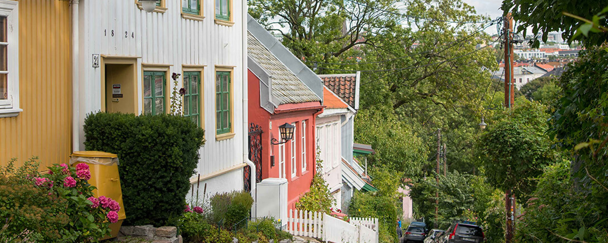 Eldre hus står på rekke og rad i en nedoverbakke