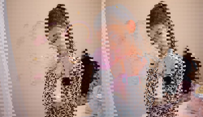 En barn koser med bamsen sin