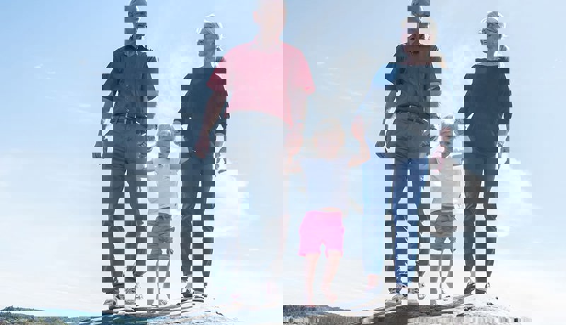 Et eldre par med et lite barnebarn går på et svaberg