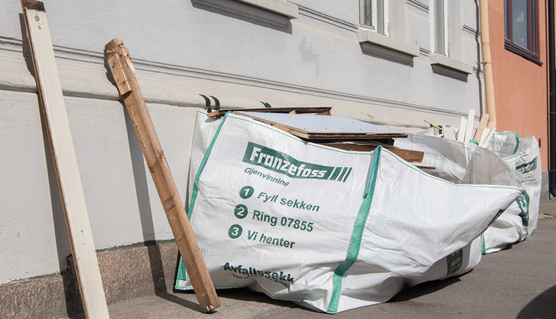 Planker og avfallsekk utenfor en boligblokk