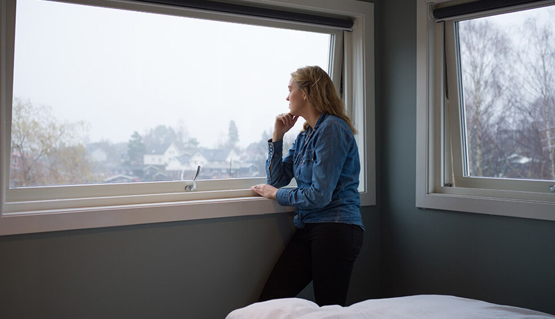 En kvinne virker tankefull mens hun ser ut av vinduet