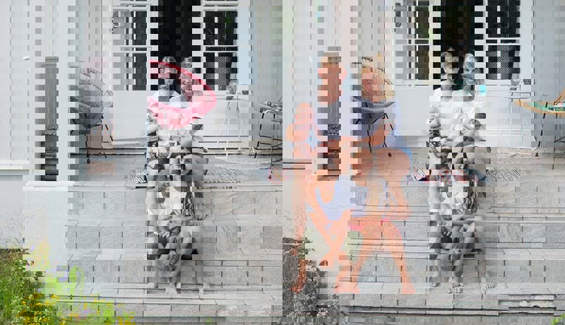 En familie sitter sammen på trappa inn til huset