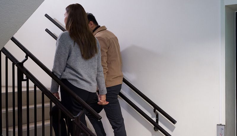 Et par holder hender mens de går opp en trapp