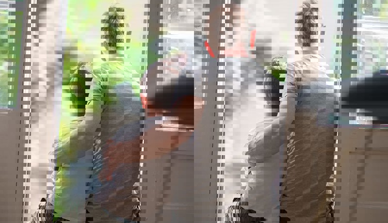 Far sitter med armen rundt sønnen sin i døråpningen