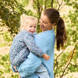 Bilde av mor som holder datter og smiler ute en sommerdag