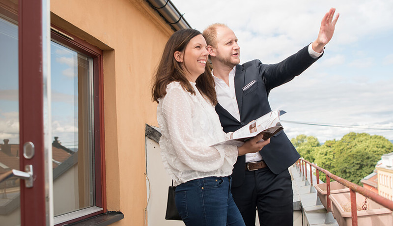 Eiendomsmegler viser kvinne utsikten fra terrassen på visning