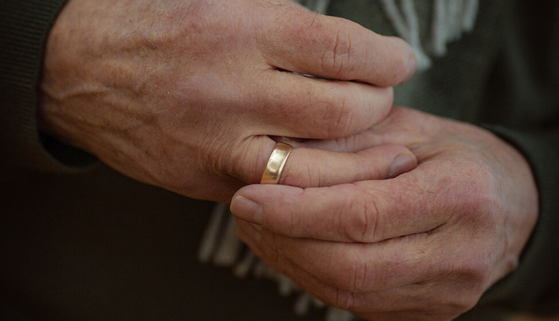 En mann holder hendende sammen og tar på gifteringen sin