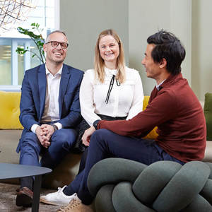 Bilde av tre personer som har det hyggelig og smiler i sofaen