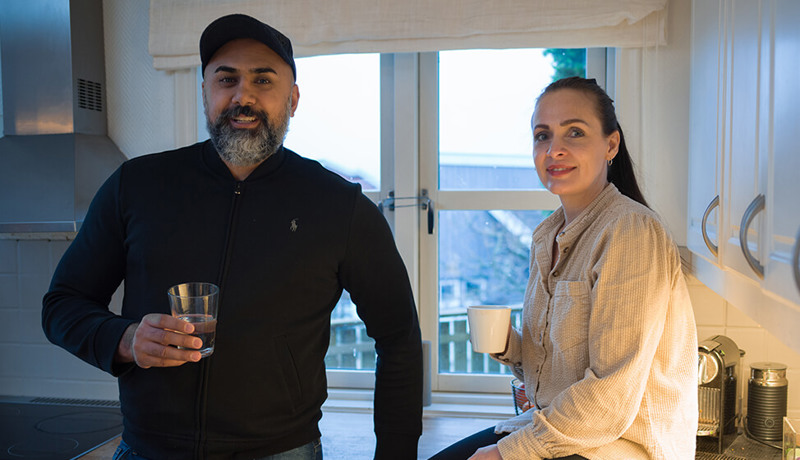 Et par smiler mens de sitter på kjøkkenet