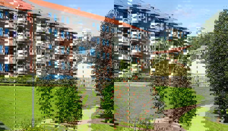 Boligbygg med vinduer, verandaer og fine grøntarealer utenfor