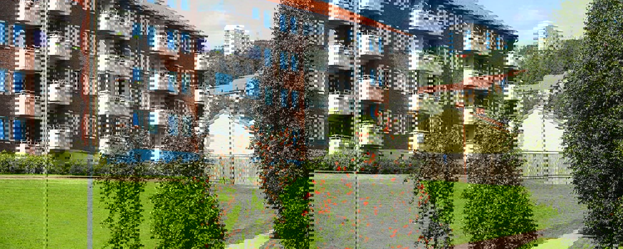 Boligbygg med vinduer, verandaer og fine grøntarealer utenfor