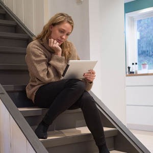 Bilde av en kvinne som sitter i trappa på et nettbrett