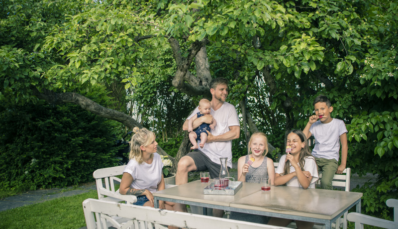 Familie på fem ved langbord drikker saft