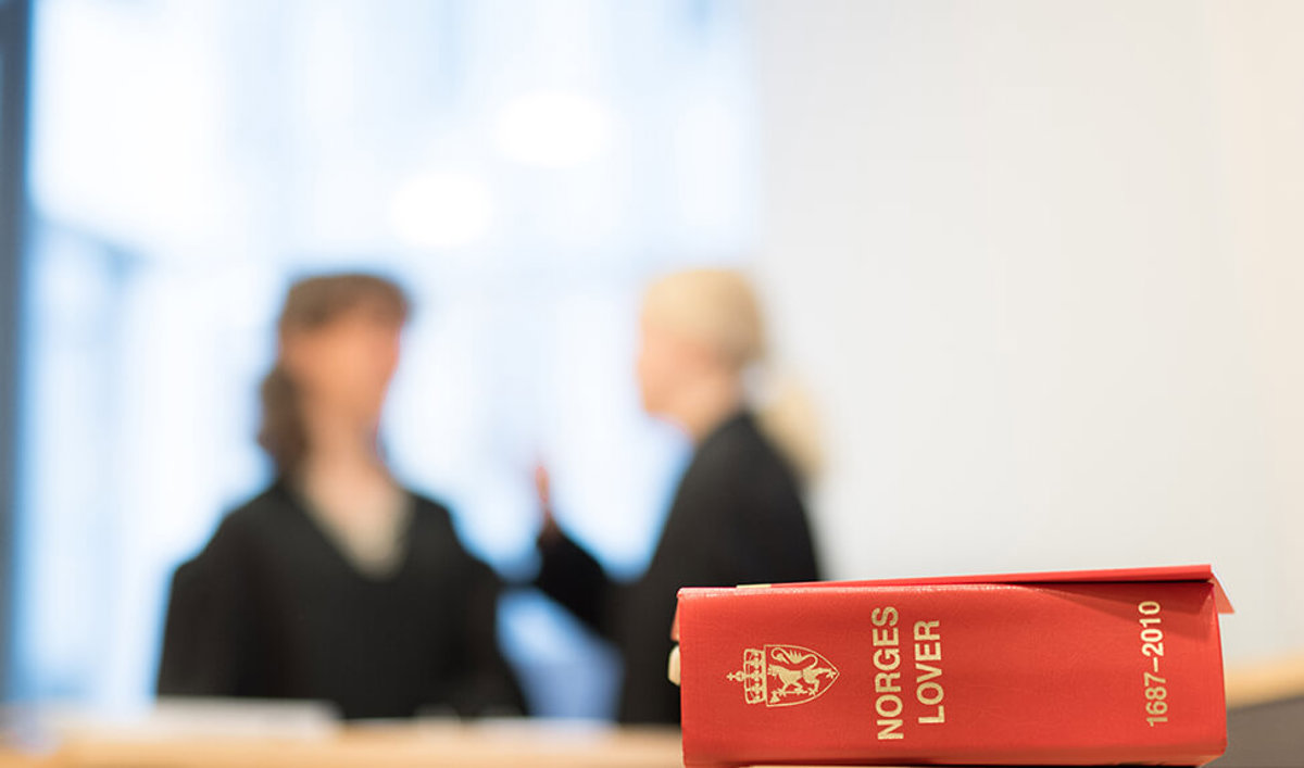 To advokater diskuterer i bakgrunnen med Norges Lover i fokus