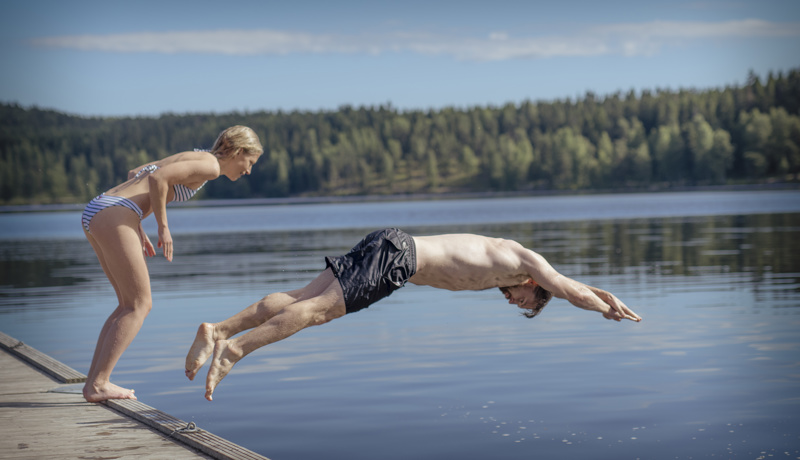 Kvinne og mann stuper ut i vannet fra brygge