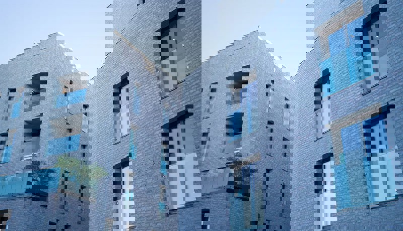 En moderne boligblokk med store vinduer og franske balkonger