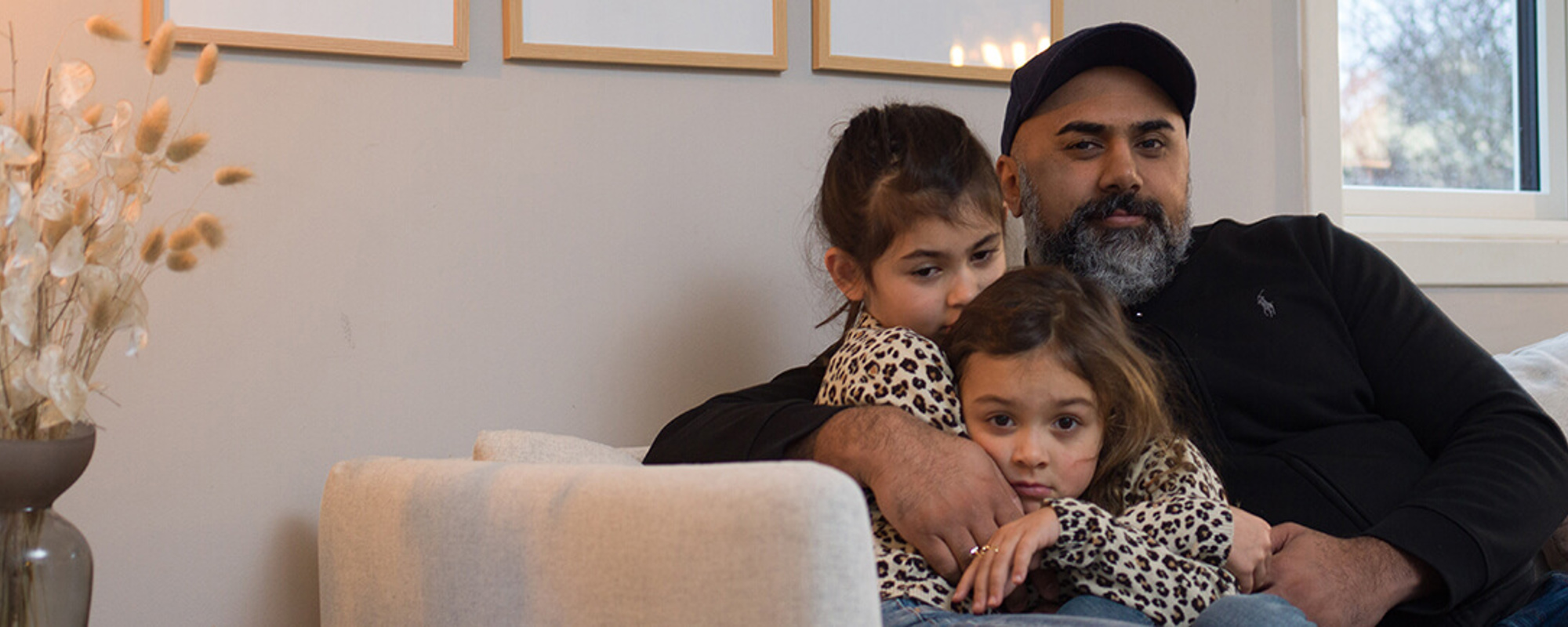 En far sitter med to barn i sofaen