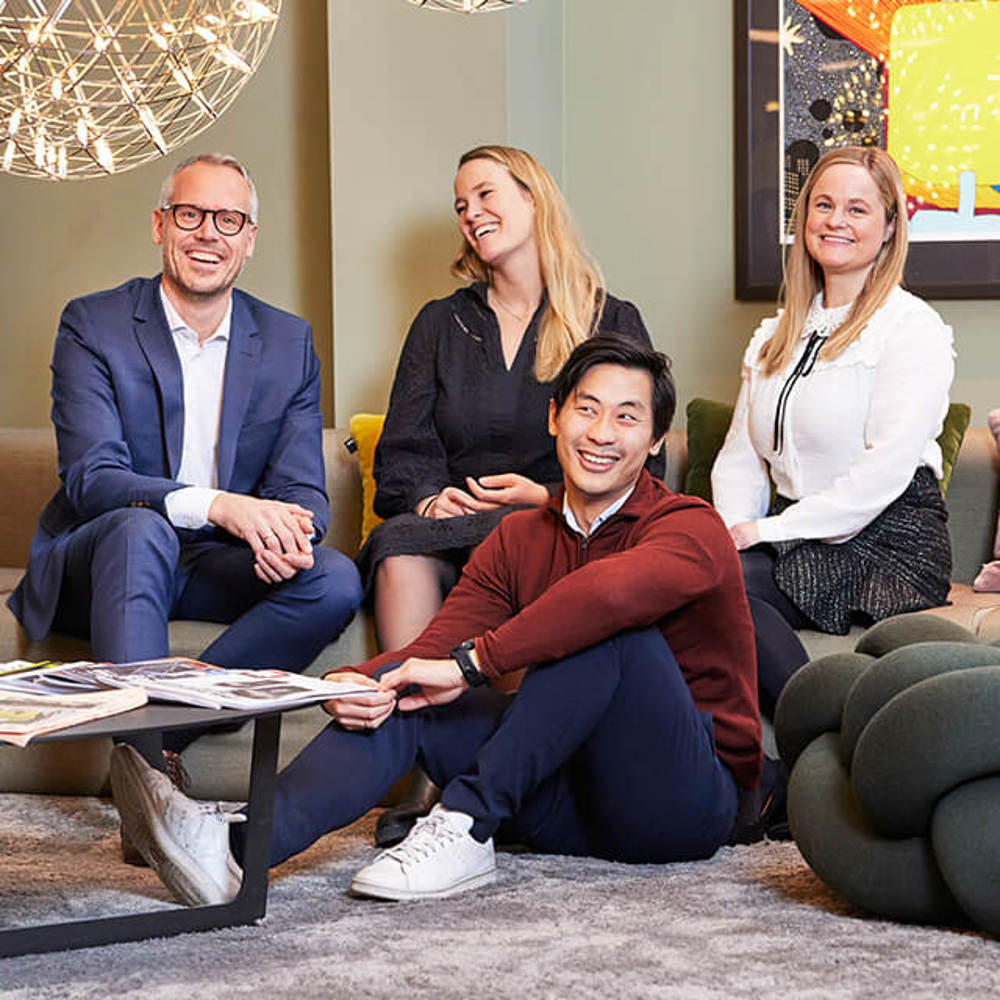 Fire ansatte sitter i sosial sone og smiler