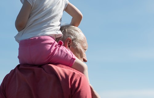Barn sitter på skuldrene til bestefar