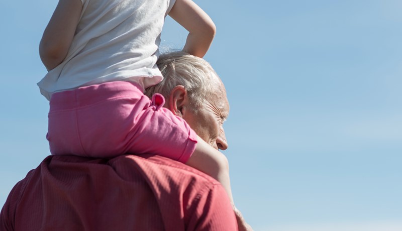 Barn sitter på skuldrene til bestefar