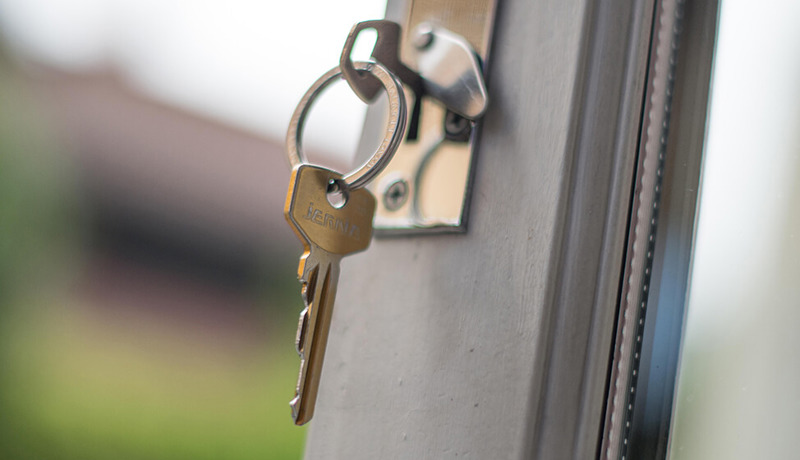 En nøkkel står plassert i låsen på en dør med vindu