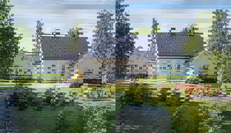 Hvit stor enebolig med stor og innholdsrik plen