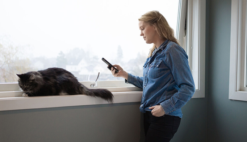 En kvinne sitter på telefonen med en katt ved siden av