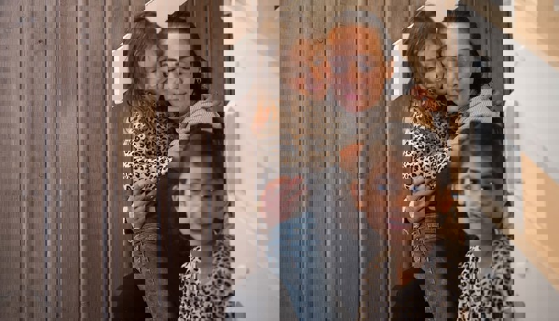 En mor sitter med to barn i trappa