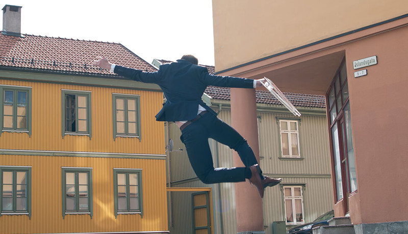 Eiendomsmegler har et visningsskilt i hånda mens han hopper av glede