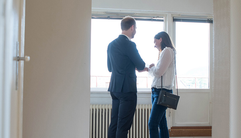 Eiendomsmegler og kvinne ser i salgsoppgaven sammen på visning