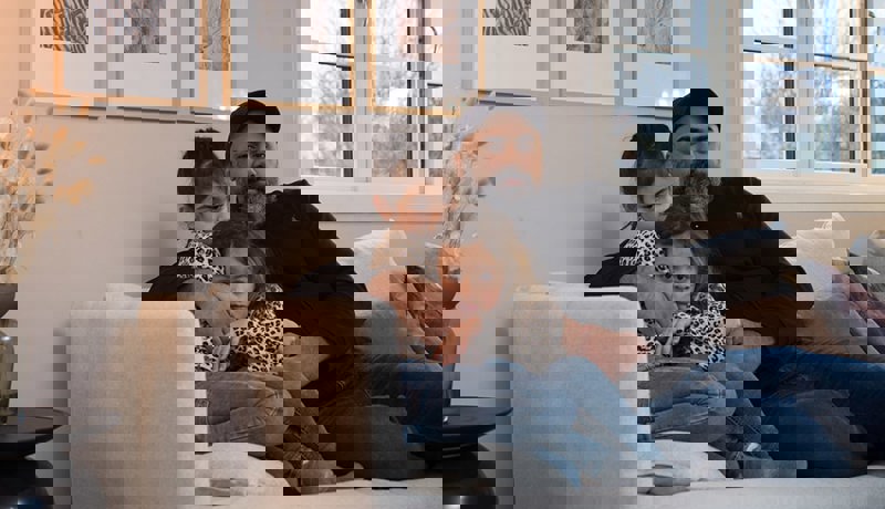 En far sitter med to barn i sofaen