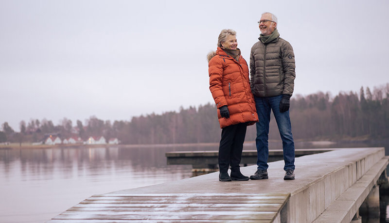 Et eldre ektepar ser glade ut mens de står på en brygge