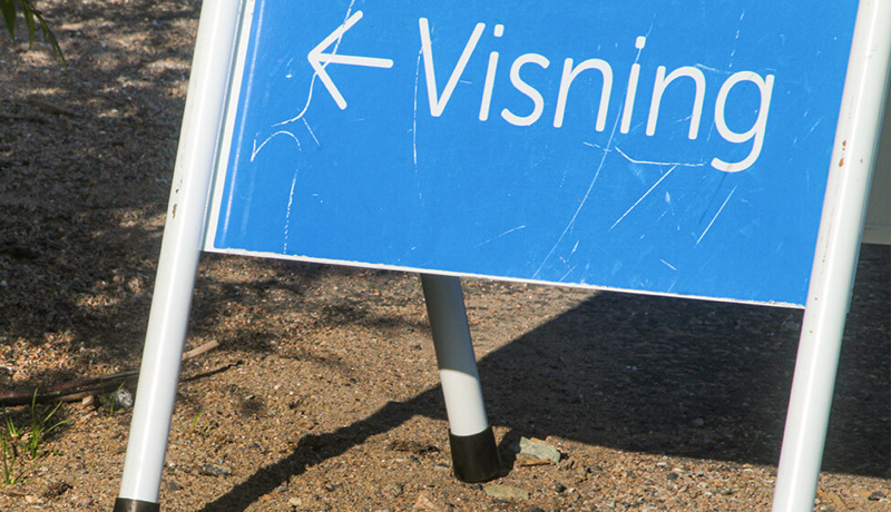 Et skilt står utendørs og peker til boligvisning