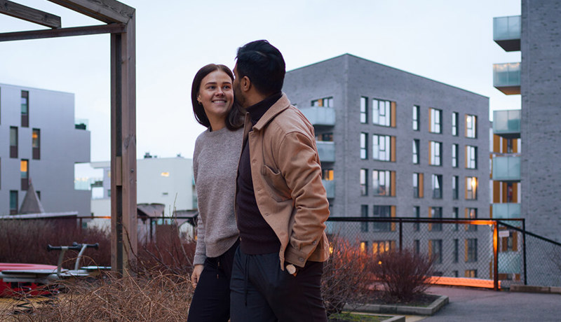 Et ungt par smiler mens de er på vei inn i leiligheten sin