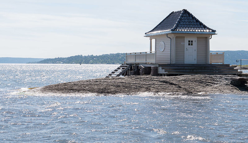 Et lite hus på en øy eller odde rett ved havet