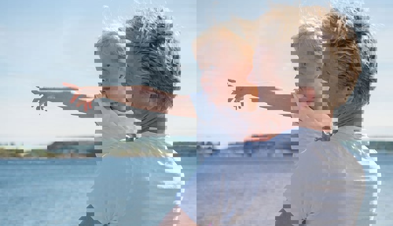 En far og en ung datter ser ut mot havet en fin sommerdag