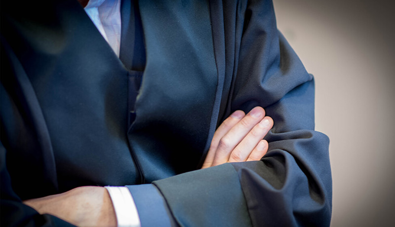 Advokat i advokatkappe med hendene i kryss